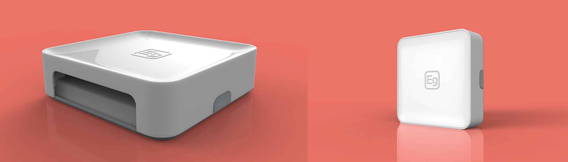 Side-by-side images of two white electronic devices with identical logos on a coral background. The left device is flat and rectangular with a slot, while the right device is upright and rectangular.