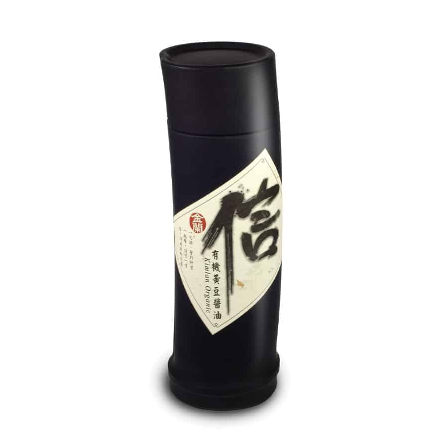 A cylindrical black bottle with a slanted, cream-colored label featuring bold Japanese characters and smaller text. The bottle has a black cap.