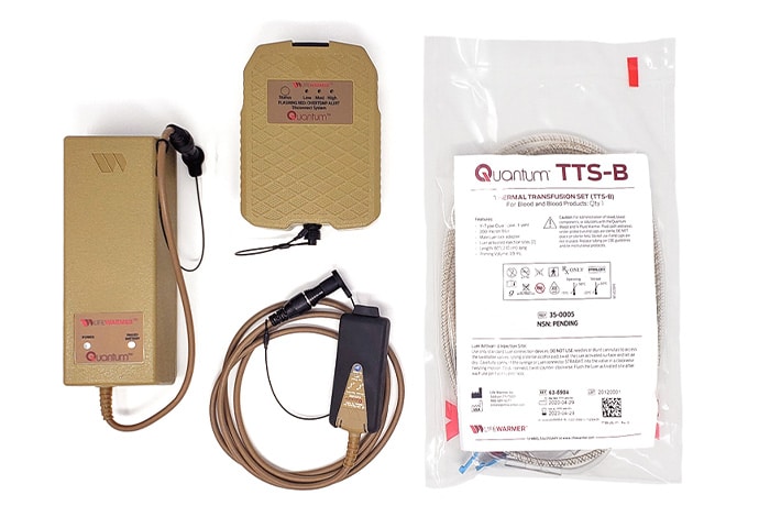Image of a Quantum TTS-B terminal training simulator set, including a tan-colored adapter, a control unit, cables, and an instruction manual in a plastic bag.